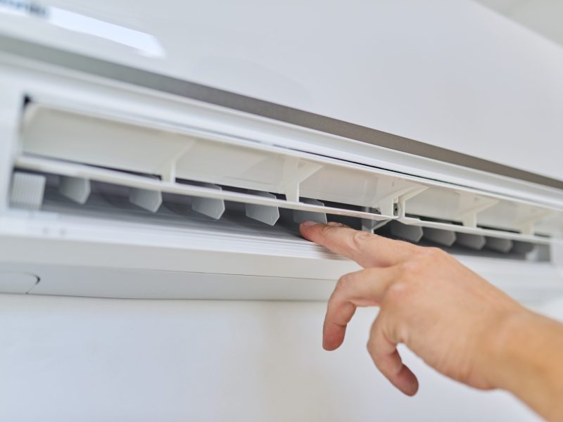 Installing an air conditioner in an apartment office, close-up of an engineer installer's hand with an indoor unit