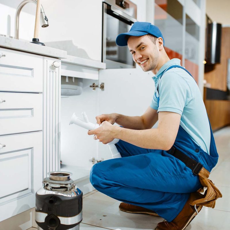 smiling-male-plumber-in-uniform-holds-drain-pipe-resize.jpg